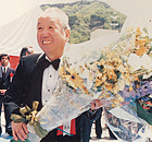 毎日新聞社ヘリコプターから開学を祝して投下された花束と受取る加計理事長（当時）